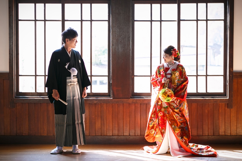 大きな窓から光が差し込む旧庁舎記念館の室内に立つ、色打掛の花嫁と紋付袴の新郎。郡上八幡での和装ロケーションフォト
