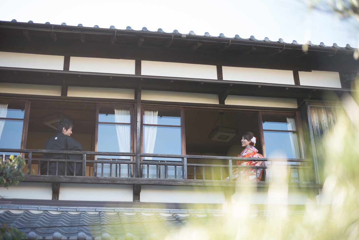 2階の縁側から庭を見下ろす色打掛の花嫁と黒紋付袴の新郎。どうだん亭の建物を生かした和装フォトウェディング