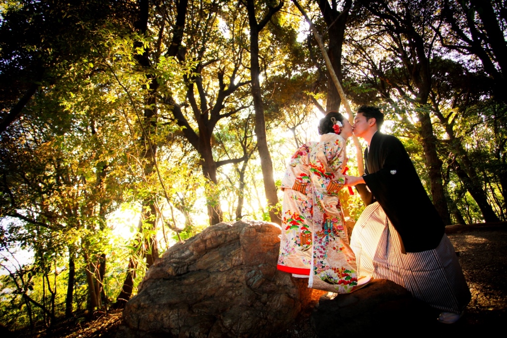 夕陽の差す木立の岩に腰を下ろす色打掛の花嫁と紋付袴の新郎。東山荘で撮るロケーションフォト