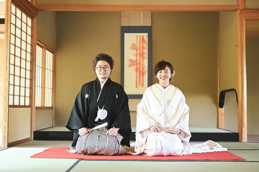 清羽亭の茶室で赤い毛氈に正座する白無垢の花嫁と黒紋付袴の新郎。所作の美しさが伝わる和装前撮り