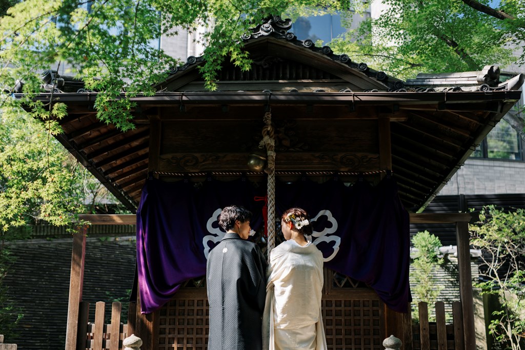 社殿の前で向かい合ってお参りをする、白無垢の花嫁と紋付袴の新郎。揚輝荘ならではの和装フォトウェディング
