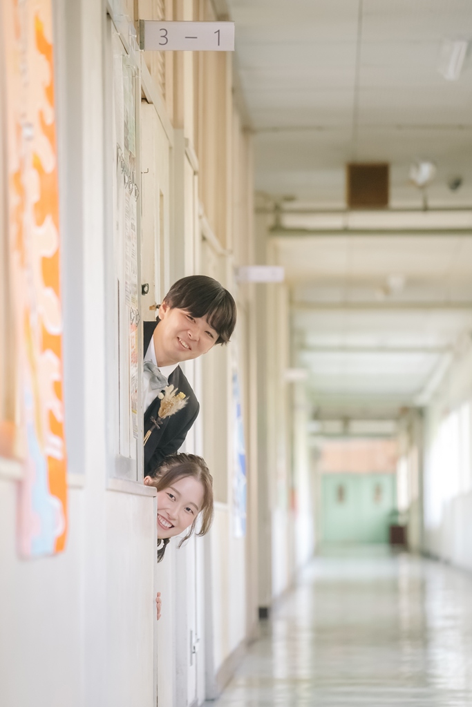 学校の教室で黒板の前に立つウェディングドレス姿の花嫁