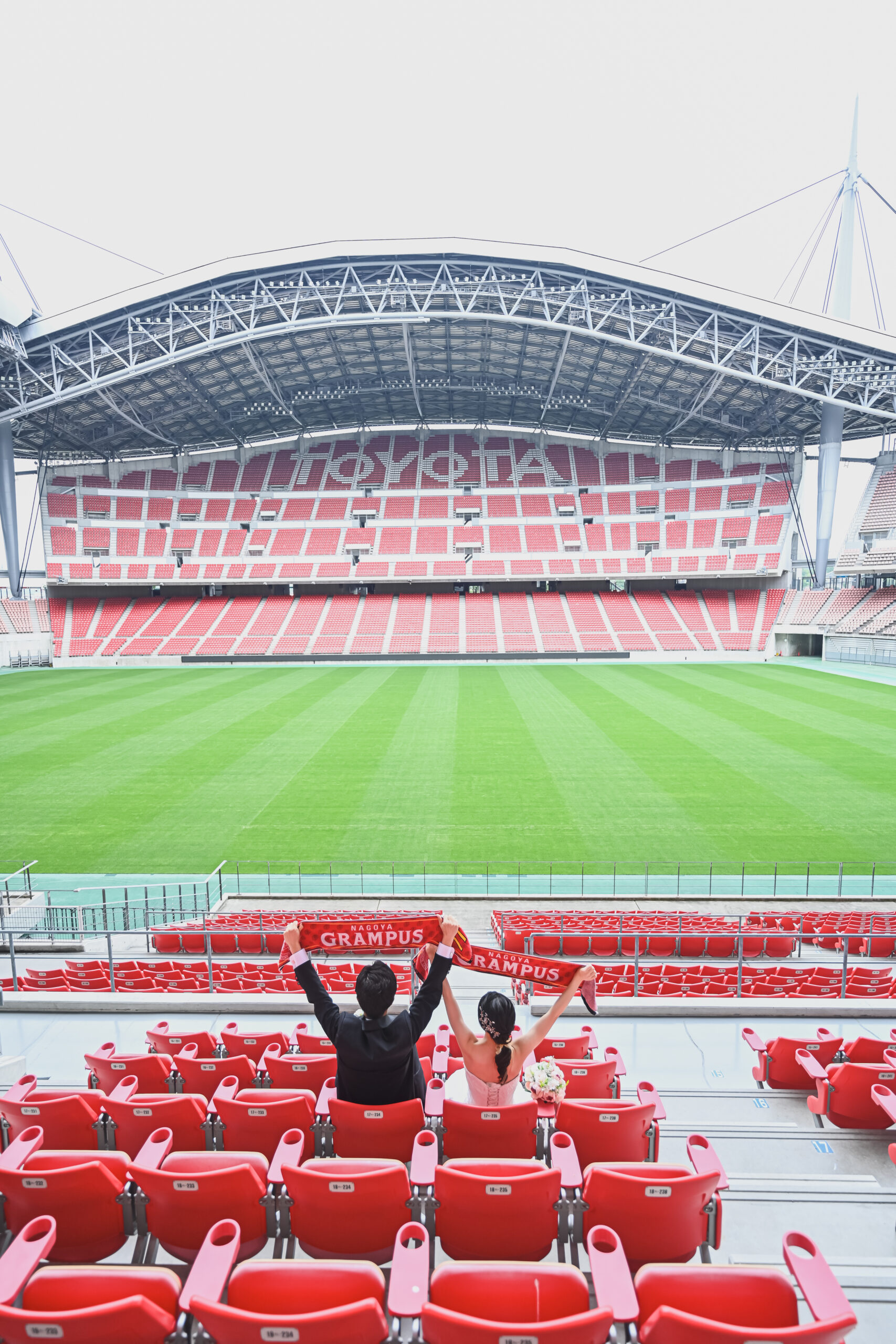 スタジアムのスタンドからピッチを背景にしたカップルの前撮り写真