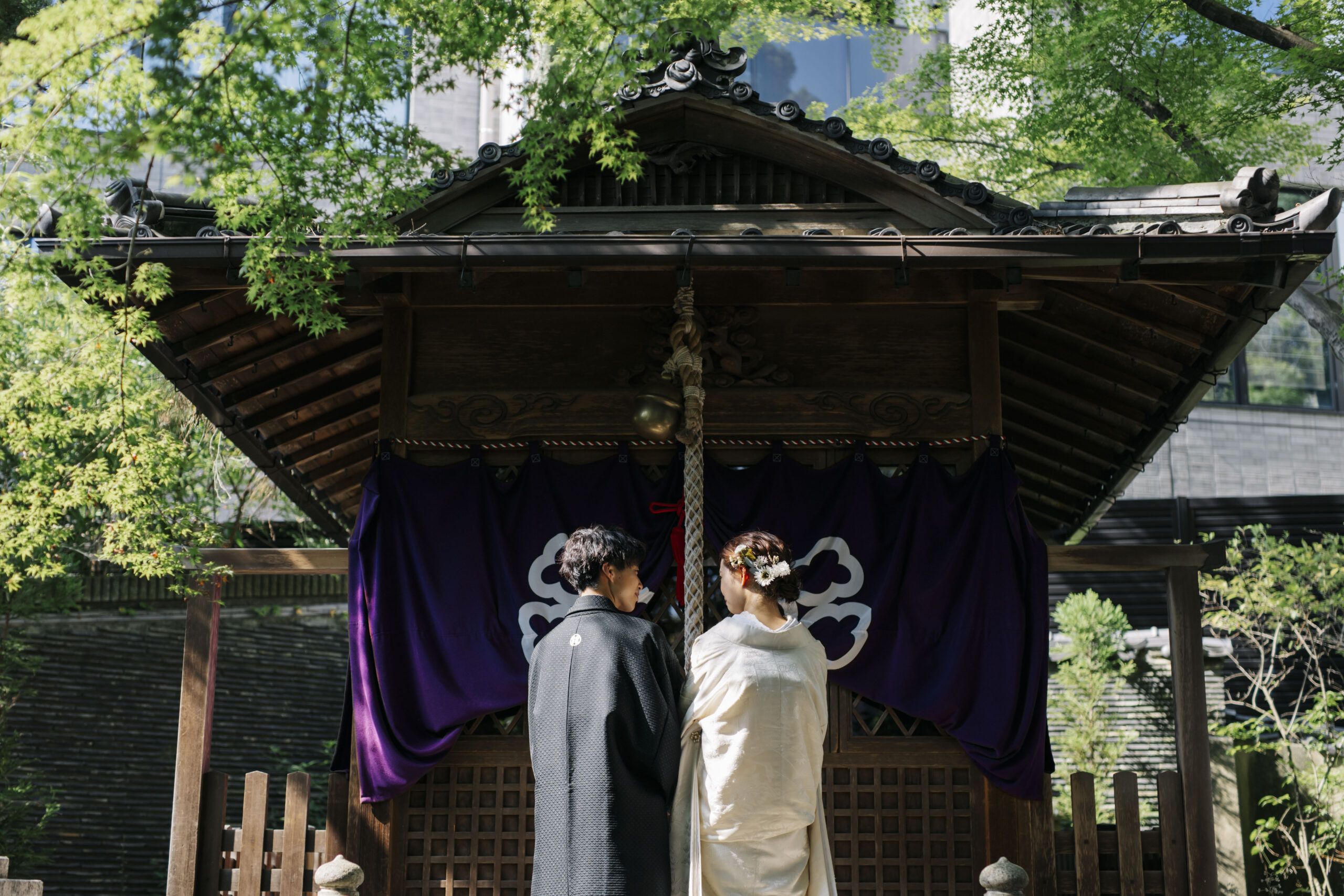 揚輝荘の緑の中で見つめ合う色打掛の花嫁と新郎