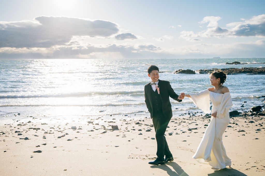 内海の波打ち際でドレスをなびかせる花嫁