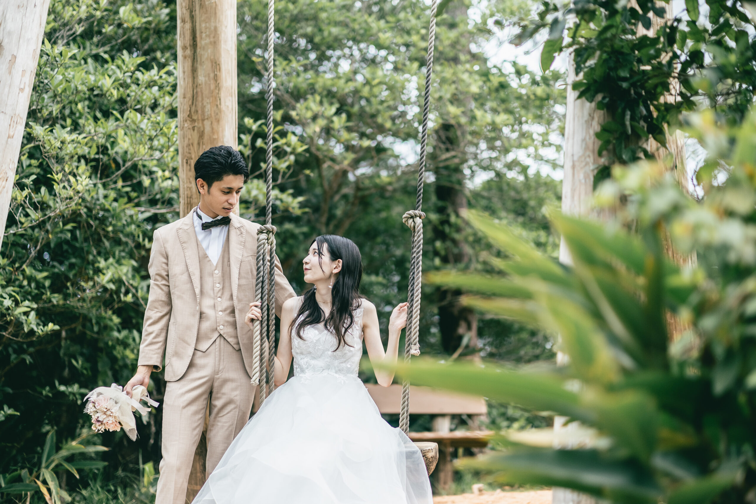 ビオスの丘の亜熱帯植物に囲まれた芝生広場でのびのびと撮影するカップルのウェディングフォト
