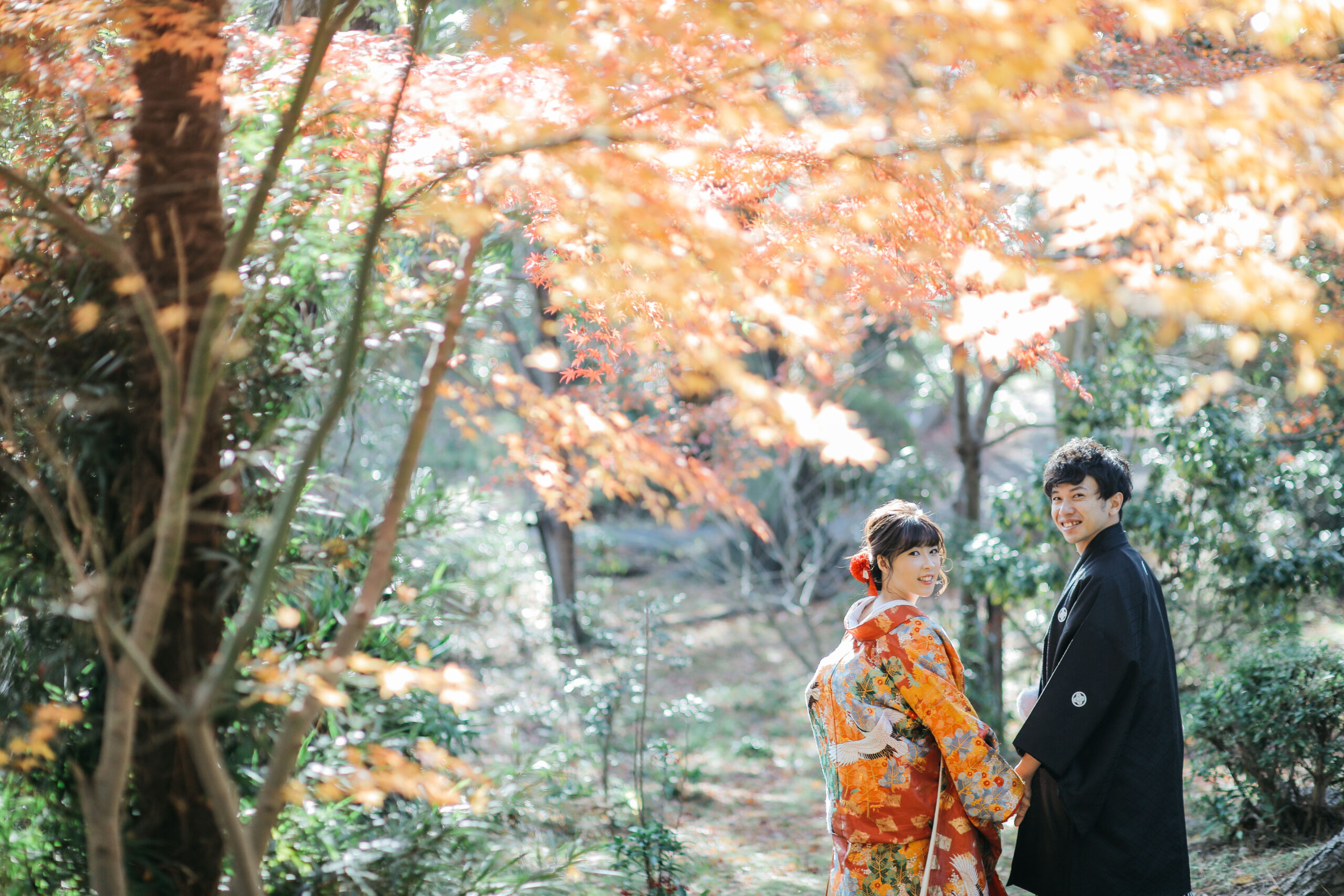 池にかかる橋の上に立つ和装の新郎新婦