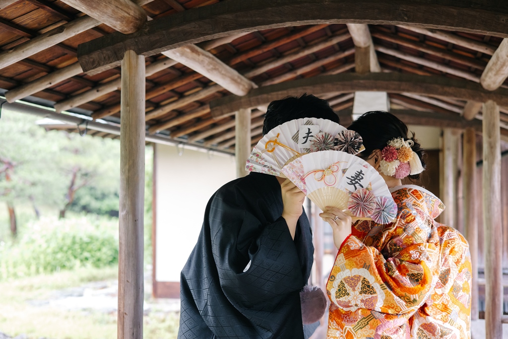 和装の花嫁が扇子を広げて凛とした表情でポーズをとる写真