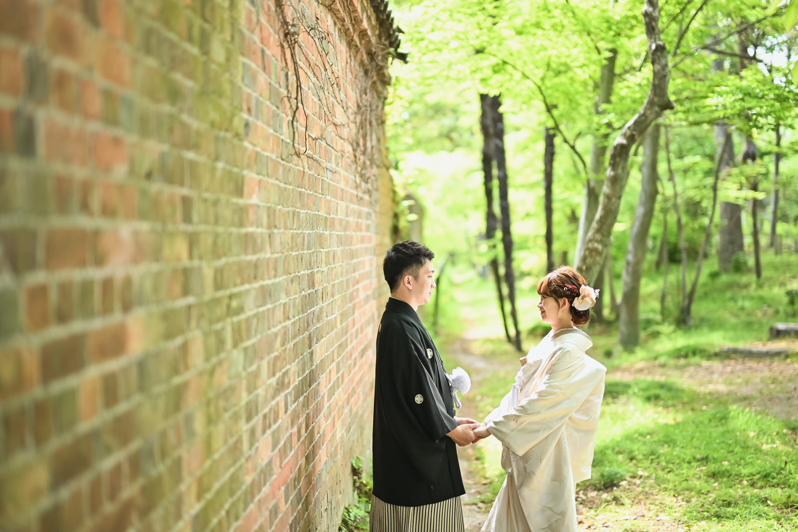 日本庭園で色打掛姿の新婦、木々を背景に