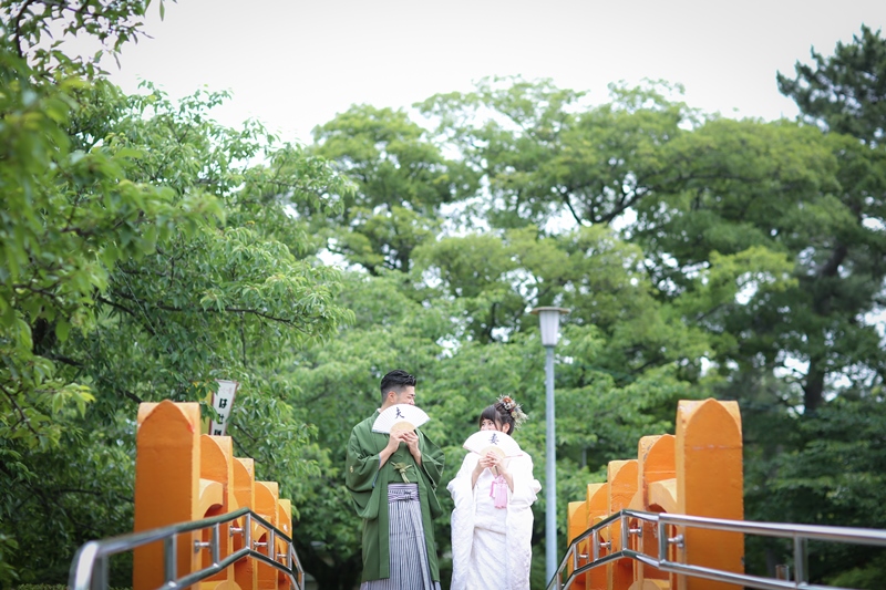 九華公園の池に架かる橋の上で並ぶ和装カップルの前撮りツーショット写真