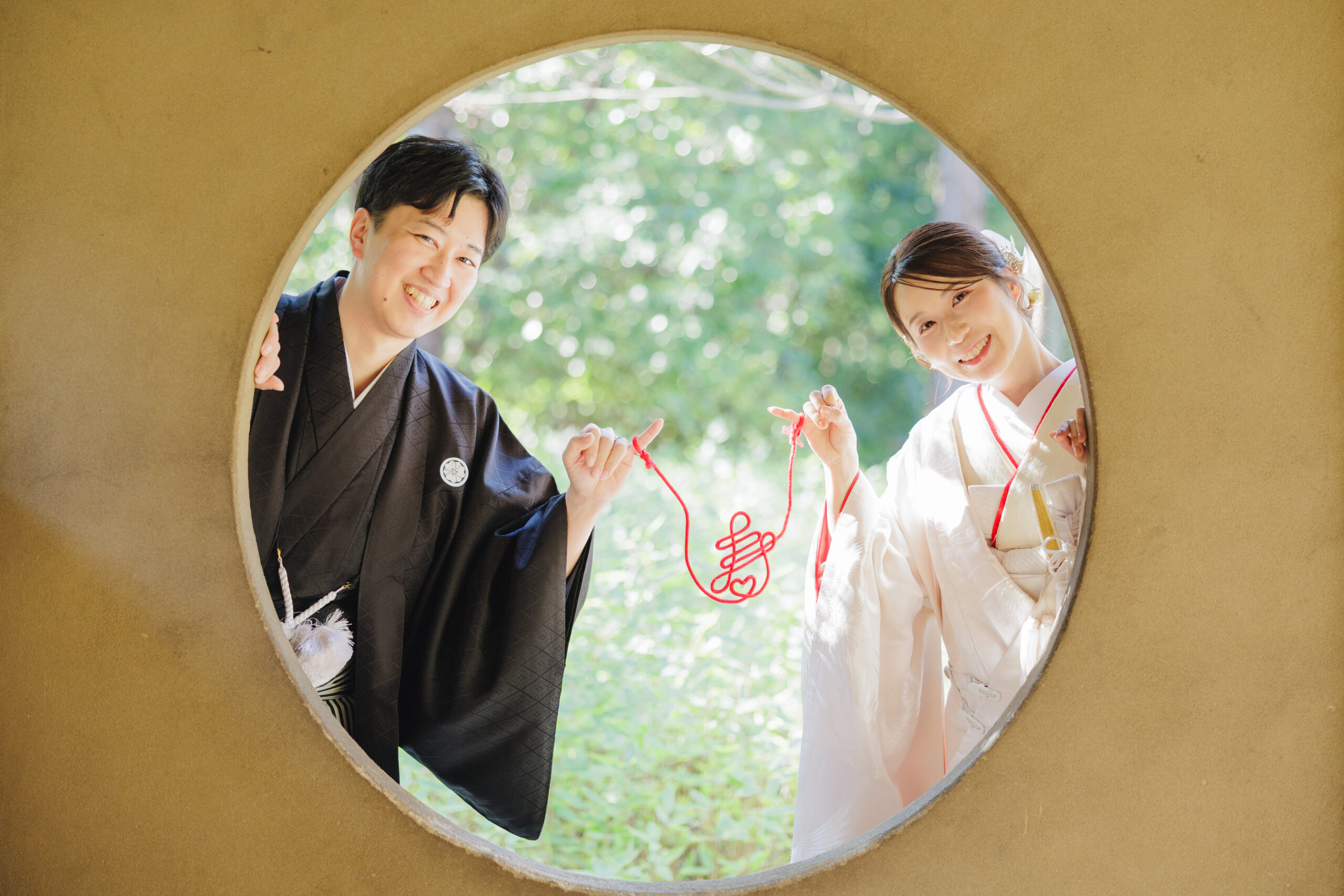 和装の花嫁と新郎が赤い糸をそれぞれ持ちふたりを繋ぐロマンチックな撮影写真