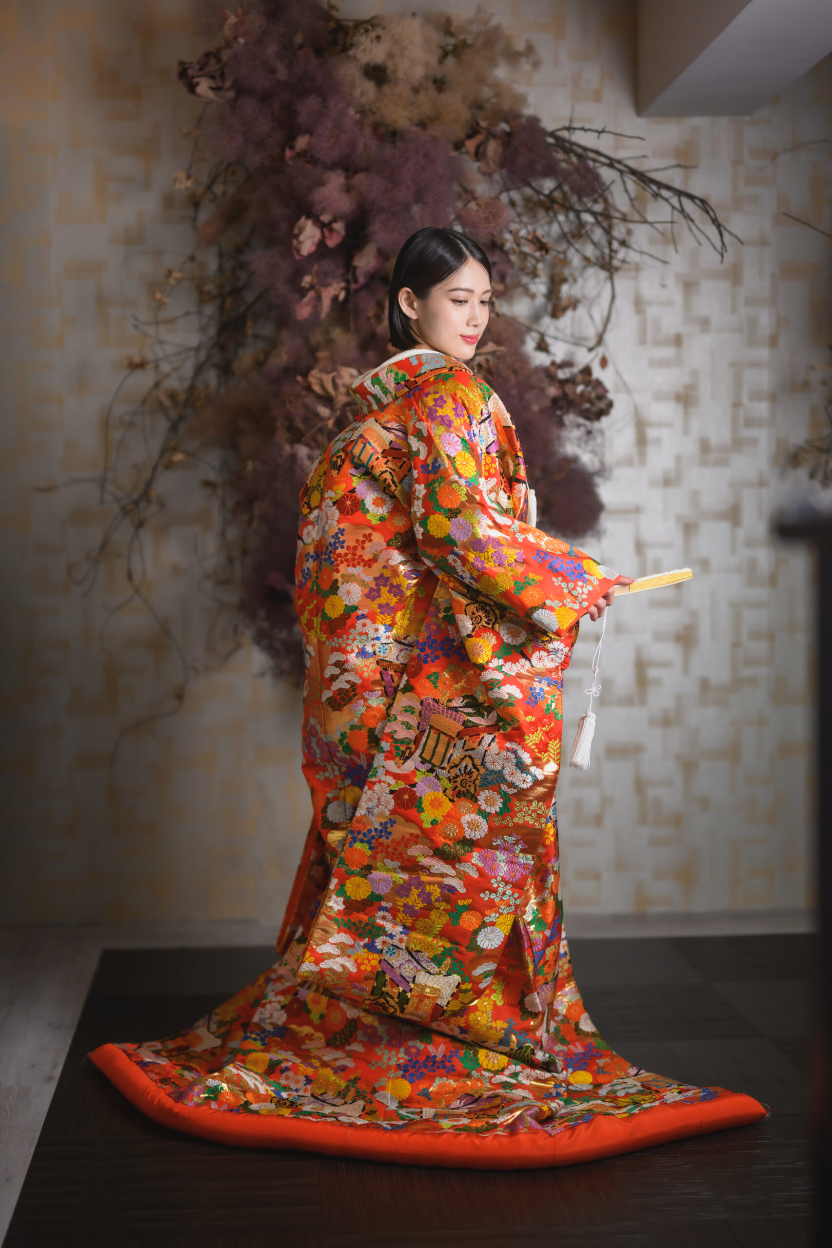 紅色地に金糸の吉祥文様が施された色打掛を纏う花嫁の全身写真