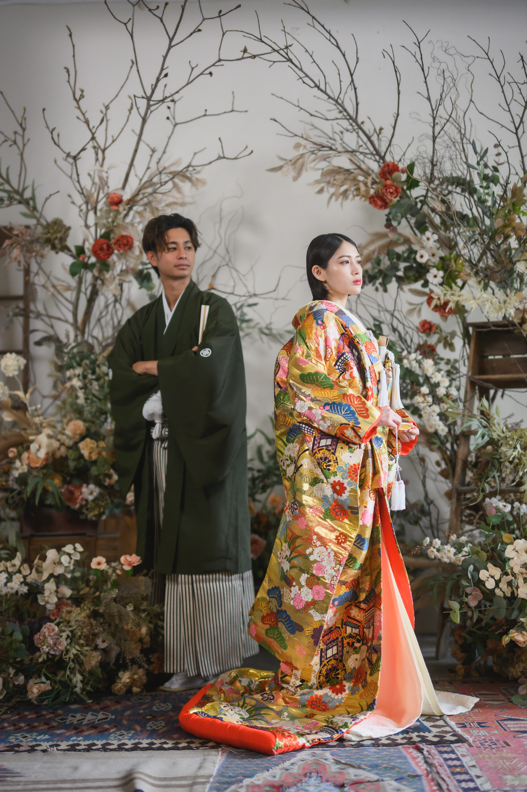 山吹色に金糸の松葉と菊の刺繍が施された色打掛を纏う花嫁の写真