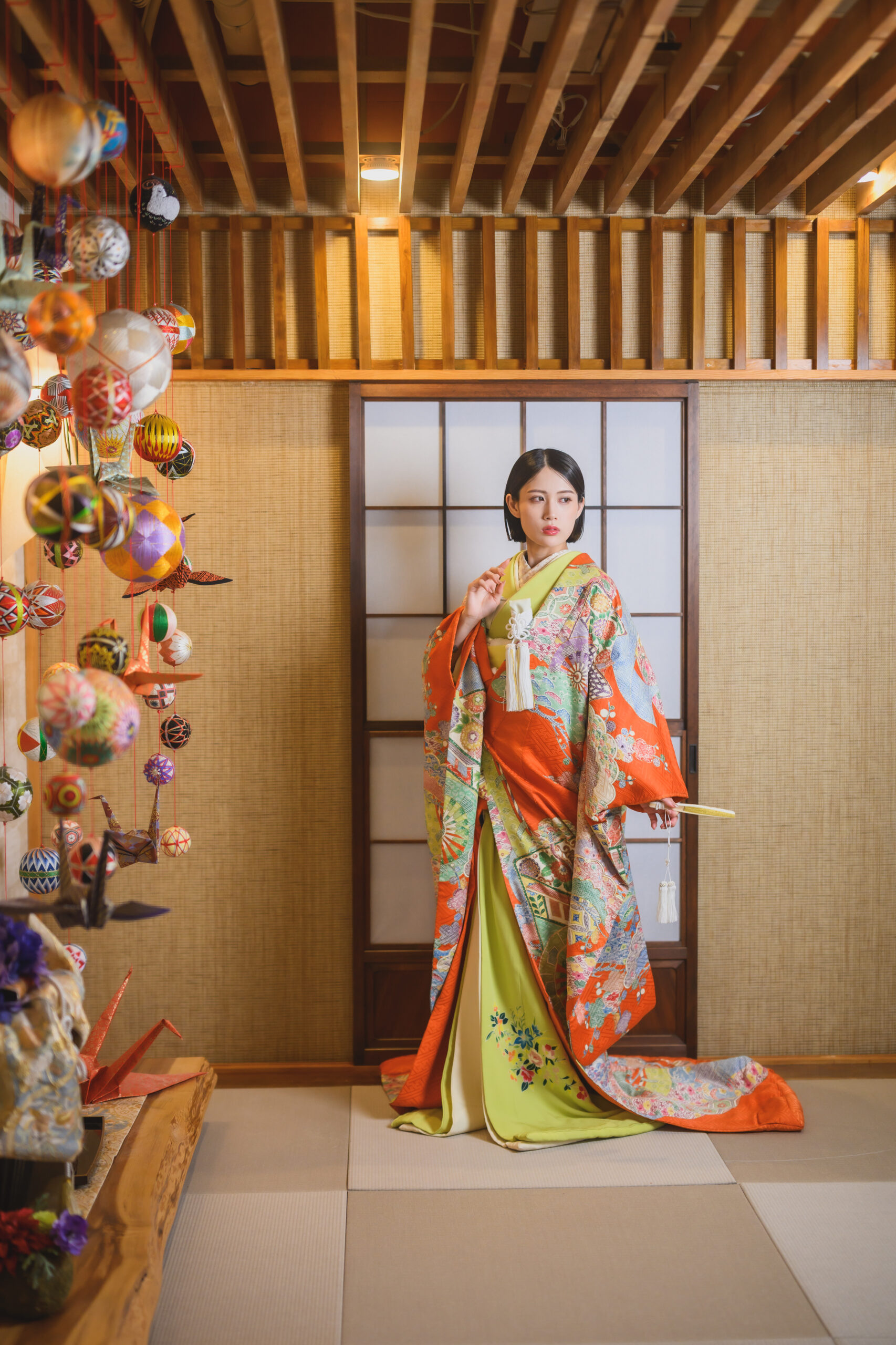 オレンジと黄緑を組み合わせた色打掛を纏う花嫁の全身写真