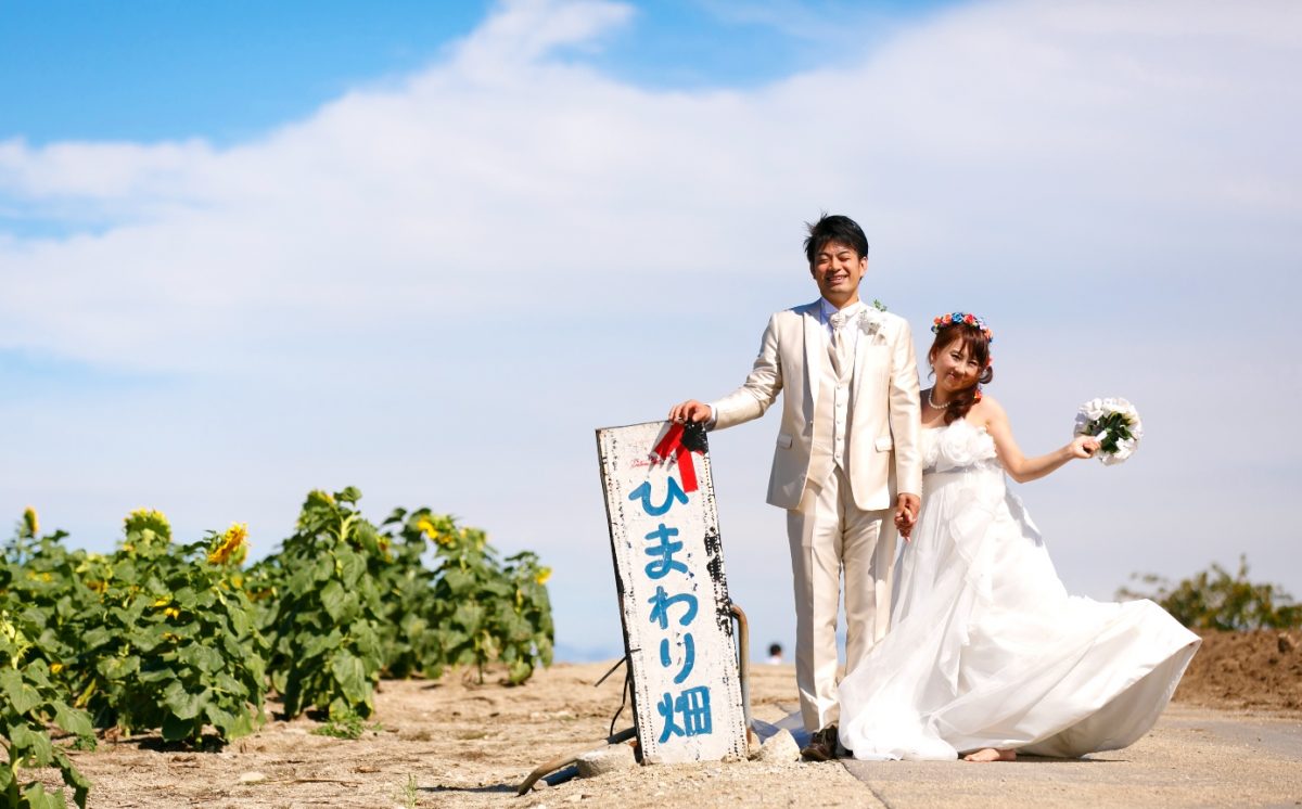ひまわり畑でドレスの裾を広げる花嫁
