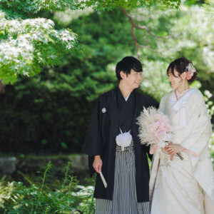 緑の木の下でピンクのブーケを持って笑い合う白い色打掛の花嫁と黒紋付袴の新郎。白鳥庭園で撮る和装前撮り