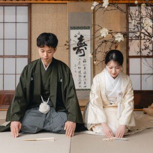 '寿'の掛け軸と障子の和室セットで、畳に手をついて礼をする黒紋付袴の新郎と白無垢の花嫁。名古屋のスタジオで撮る和装前撮り