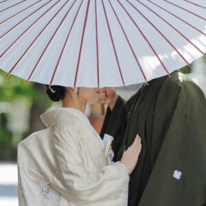 白い和傘の下で新郎の胸に手を添える白無垢の花嫁。顔を隠した構図がおしゃれな和装前撮り