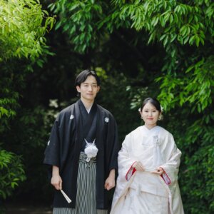竹と緑を背に並んで立つ黒紋付袴の新郎と白無垢の花嫁。白鳥庭園で撮る和装前撮りの正面カット