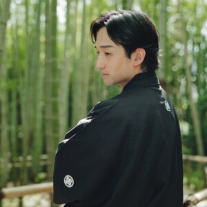 白鳥庭園にて、竹林で腕を組んで横を向く黒紋付袴の新郎の上半身カット。和装前撮りの新郎ポートレート