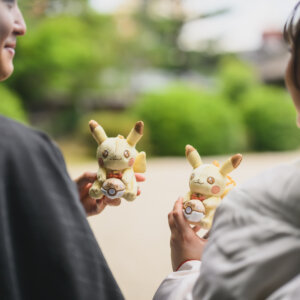 ぬいぐるみを手に持って向かい合う黒紋付袴の新郎と白無垢の花嫁の手元。ぬいぐるみを使った和装前撮りのアイテムカット