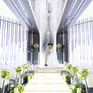 祭壇の上でキスする新郎新婦を、バージンロードの先から左右対称に撮ったチャペルフォト。光を取り込んだ明るい空間が印象的