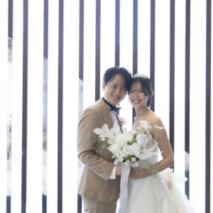 縦のラインが美しい窓辺で、白いブーケを持って頬を寄せ合う新郎新婦。ラグナヴェール名古屋で撮るチャペルフォト