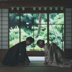 庭に面した和室で向かい合ってお辞儀をする黒紋付袴の新郎と色打掛の花嫁。日本家屋で撮る和装前撮り
