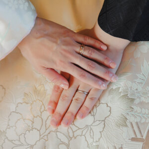 白鳥庭園にて、白い色打掛の膝の上に重ねた新郎新婦の手と結婚指輪のアップ。和装前撮りの指輪カット