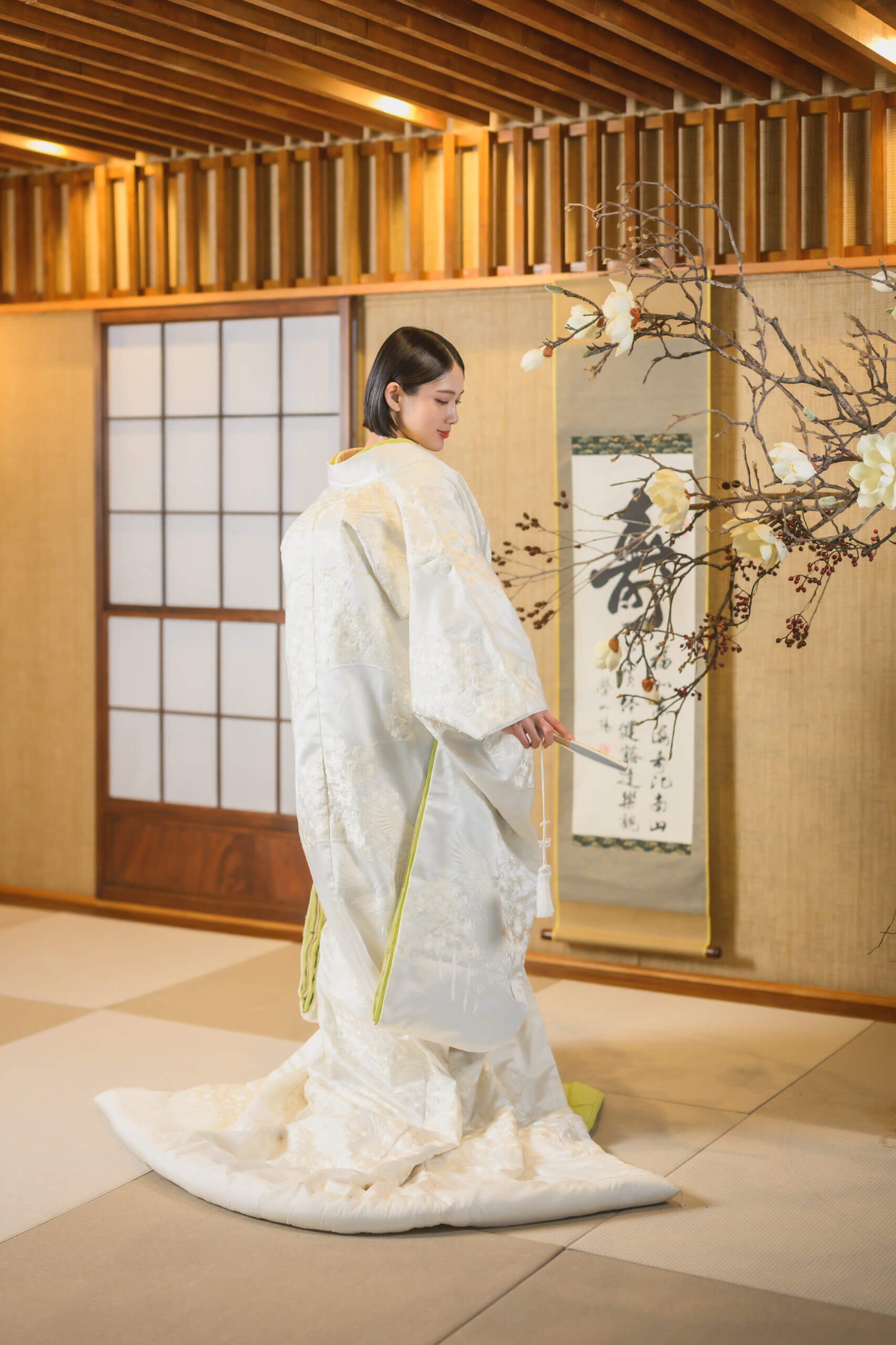 扇子を手に振り返る白無垢の花嫁の後ろ姿。長い引き裾を畳いっぱいに広げた、名古屋のスタジオでの和装前撮り