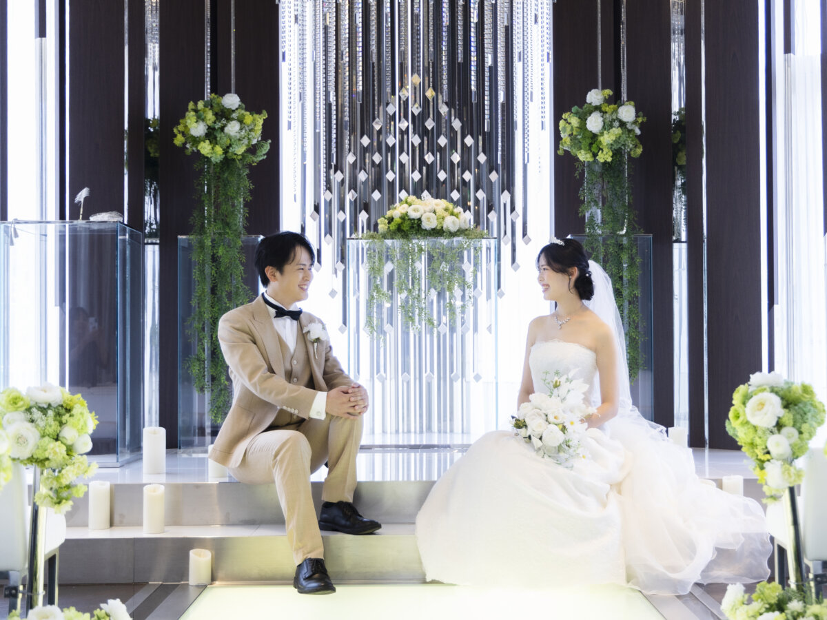 クリスタルの祭壇前の階段に腰かけて見つめ合う新郎新婦。ラグナヴェール名古屋のチャペルで叶える、写真だけの結婚式