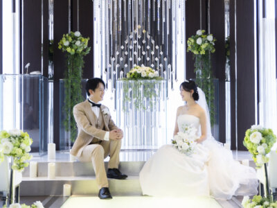クリスタルの祭壇前の階段に腰かけて見つめ合う新郎新婦。ラグナヴェール名古屋のチャペルで叶える、写真だけの結婚式
