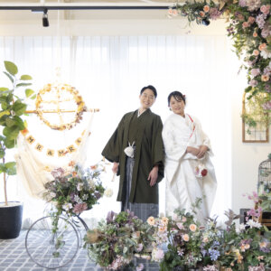 パステルカラーのフラワーウォールと'MR & MRS'のハンモックを飾ったスタジオに並ぶ羽織袴の新郎と白無垢の花嫁。名古屋のスタジオフォト