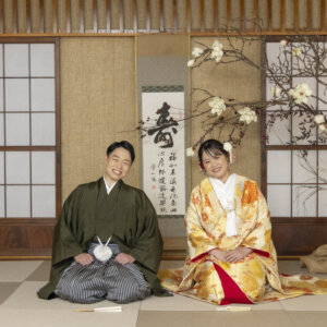 寿の掛け軸と白い花木を飾った畳の和室で、正座して並ぶ羽織袴の新郎と色打掛の花嫁。名古屋の和室スタジオで撮る和装の結婚写真