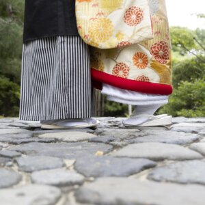 石畳の上に並ぶ、縞袴の新郎と赤い裾を効かせた金色の色打掛の花嫁の足元。白鳥庭園で撮る和装前撮りの足元カット